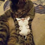 Katze riecht an Häkelpuppe Murkl