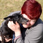 schwarzer hund Benni leckt an nase von frau